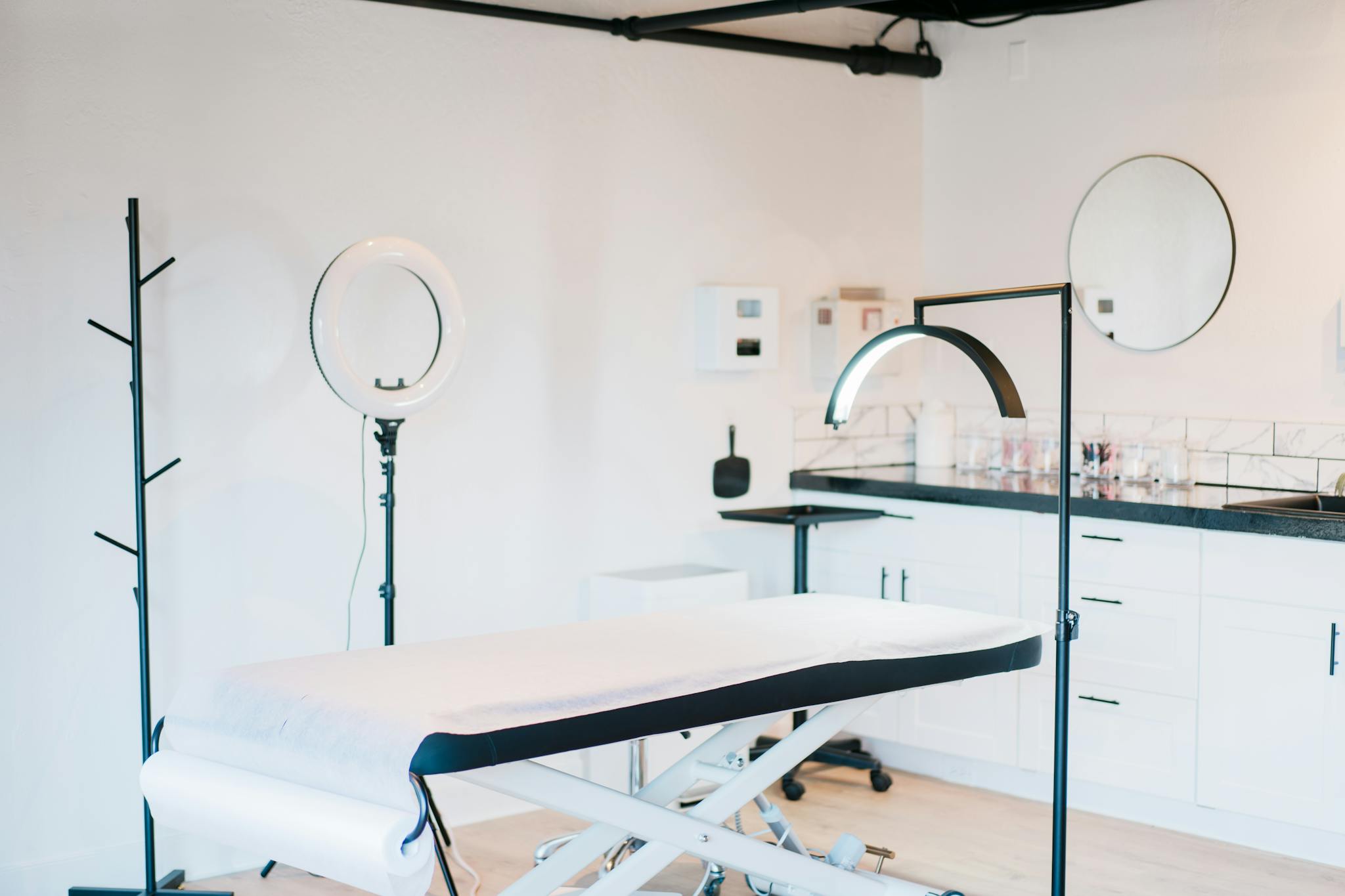 Bright and modern medical spa room featuring massage bed and studio lighting.